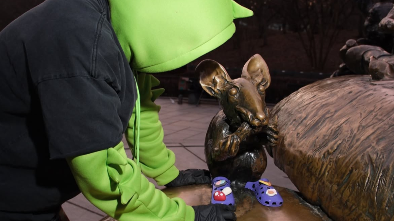 Man with hoodie with a statue with Crocs